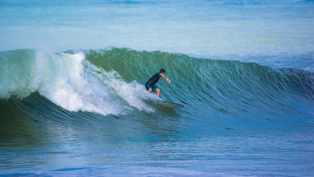 Surferin auf einer schönen Welle in den Tropen und es geht darum ohne Angst zu surfen.
