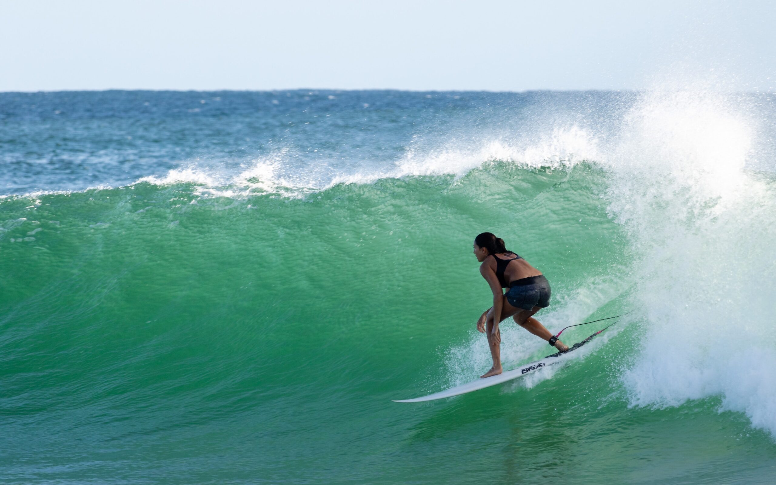 Surferin auf einer schönen Welle in den Tropen und es geht darum ohne Angst zu surfen.